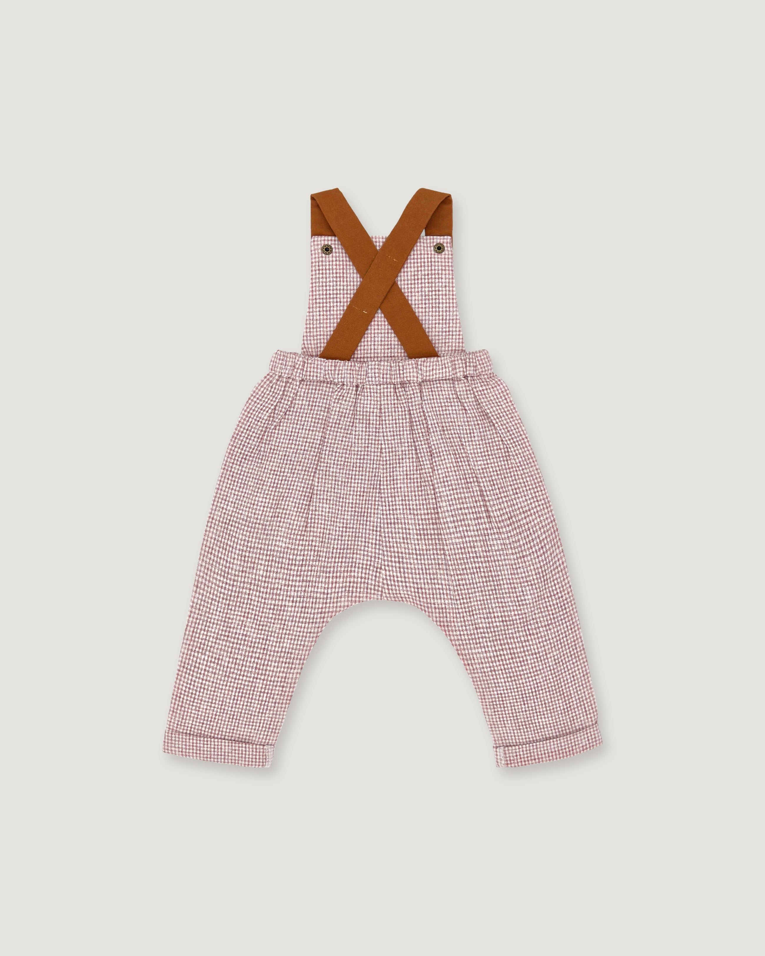 A baby romper with pink and white micro-check patterned pants, brown suspenders, and an elastic waistband, shown flat on a light gray background.