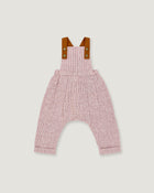 A baby romper with a pink and white micro-check pattern, featuring brown leather-like shoulder straps with snap buttons, shown flat on a light gray background.