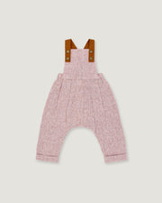 A baby romper with a pink and white micro-check pattern, featuring brown leather-like shoulder straps with snap buttons, shown flat on a light gray background.