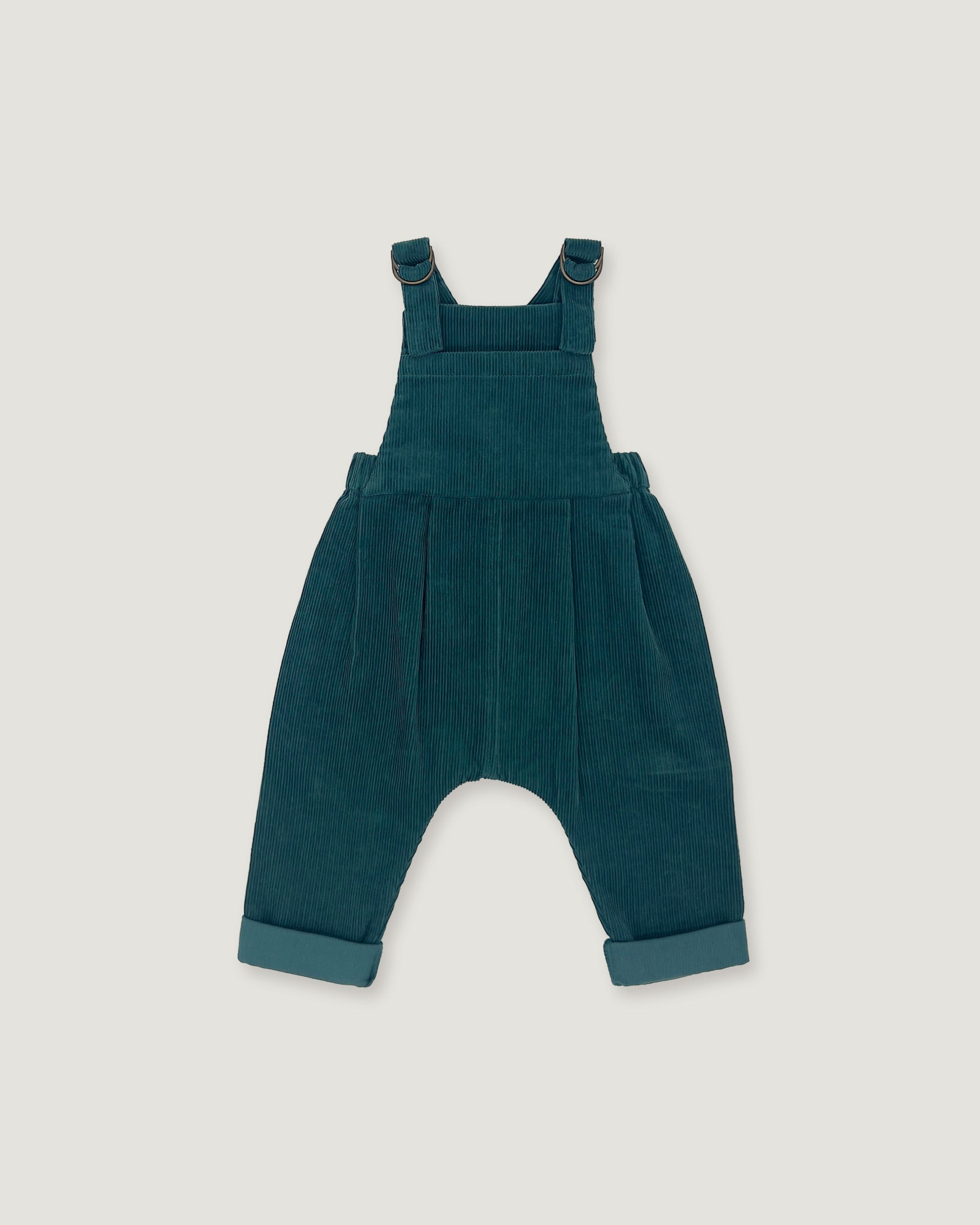 A pair of toddler corduroy overall jumpsuit in a deep teal blue-green color, featuring adjustable shoulder straps that cross over the chest and cuffed harem-style legs, shown flat on a light gray background.