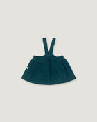 A dark teal corduroy baby skirt with adjustable shoulder straps, laid flat on a light beige background.