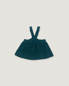 A dark teal corduroy baby dress with shoulder straps, laid flat on a light gray background.
