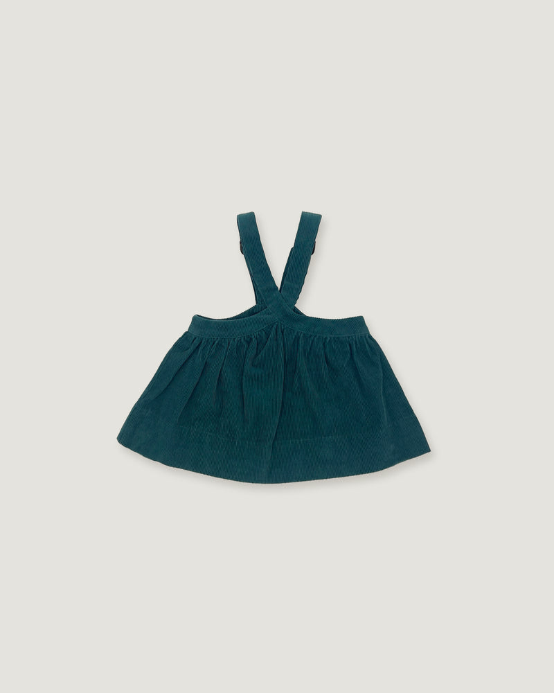 A dark teal corduroy baby dress with shoulder straps, laid flat on a light gray background.