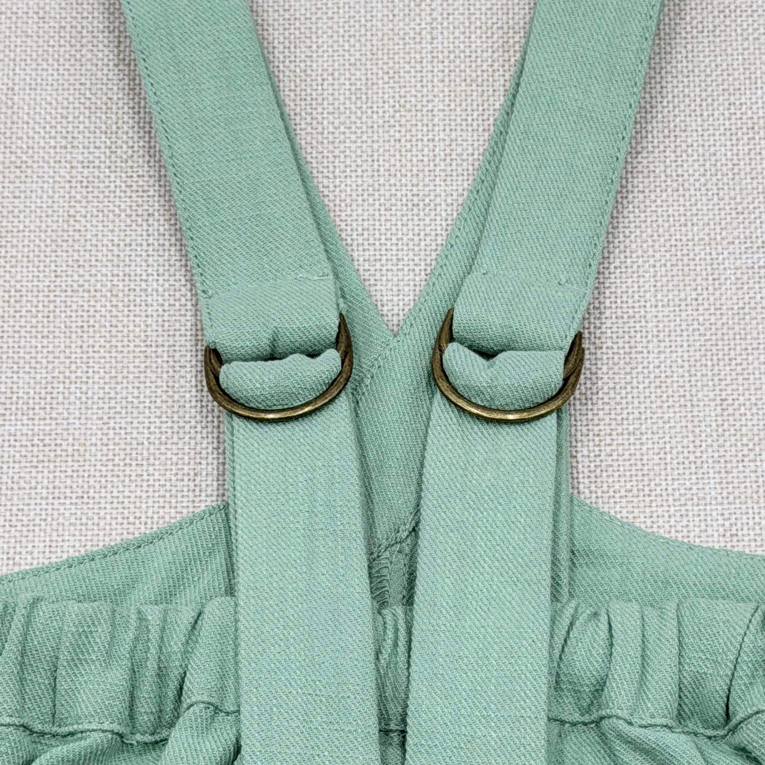 Close-up of a mint green dress with suspenders on a light gray background