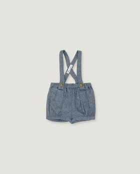 A pair of toddler boy's denim shorts with adjustable shoulder straps, featuring a textured blue-gray fabric and small gold-tone snap buttons at the waistband, shown flat on a light beige background.