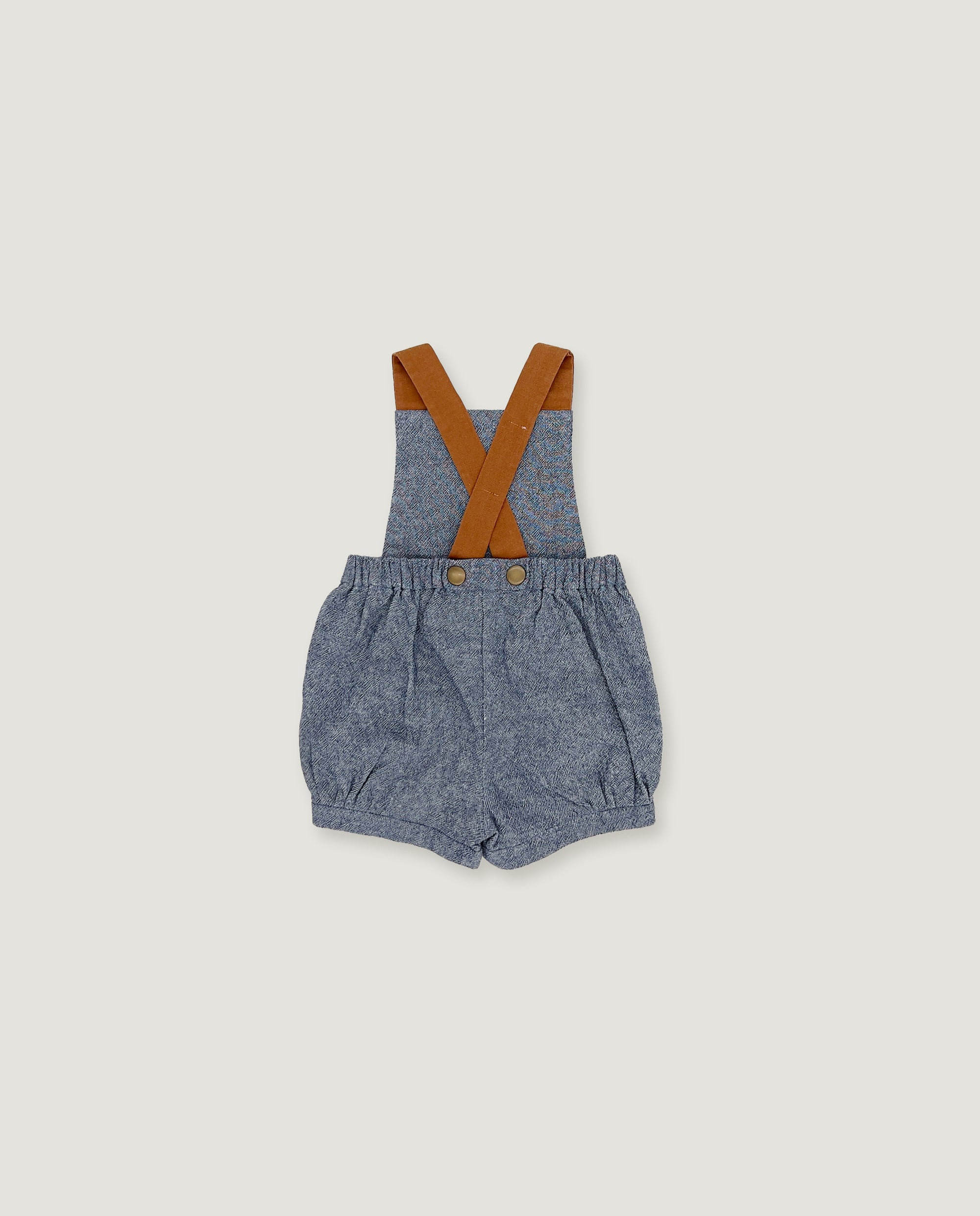 A pair of baby boy's blue-gray denim bib shorts with brown suspenders, laid flat on a light gray background.
