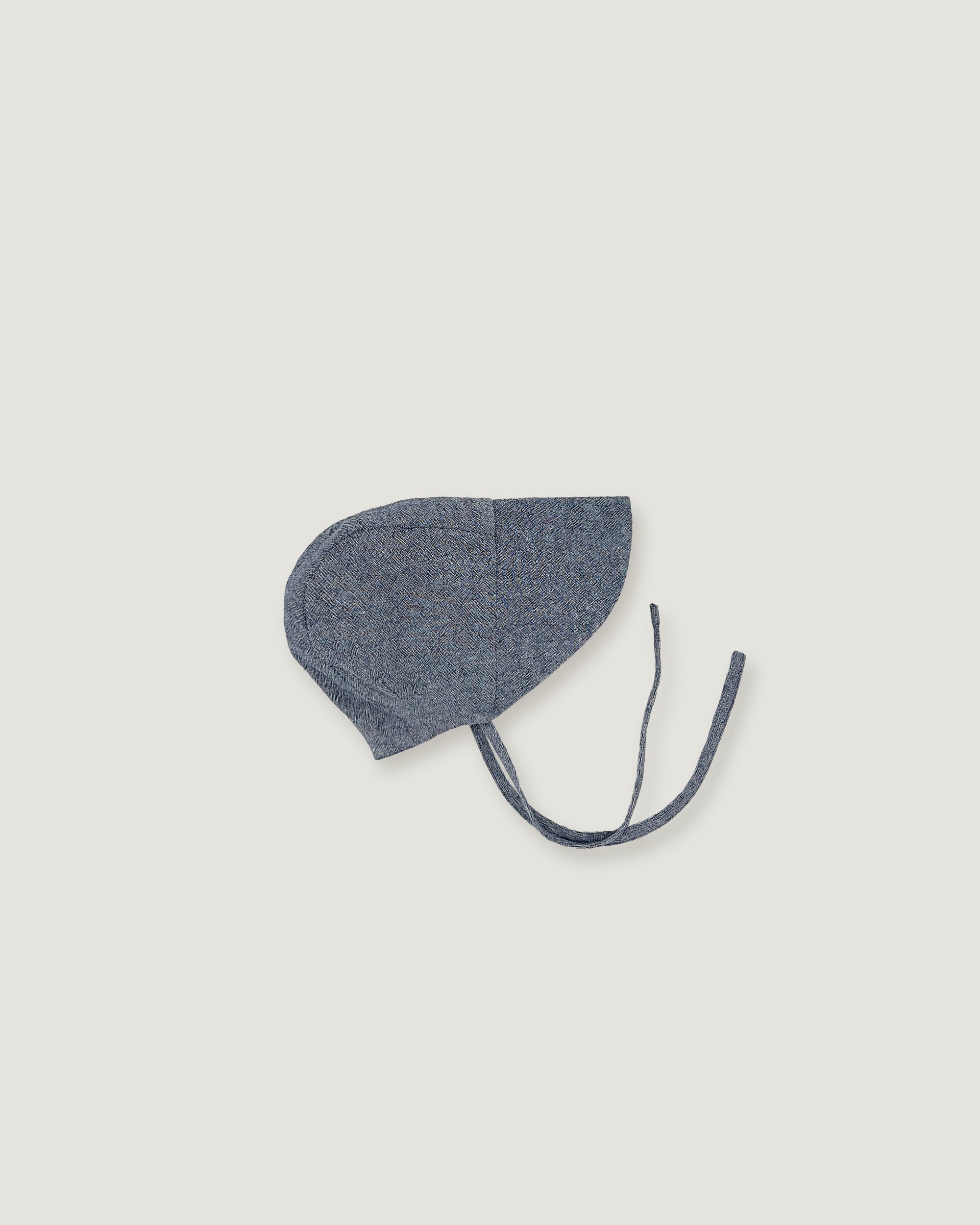 A denim blue linen bonnet with a long visor on a white background