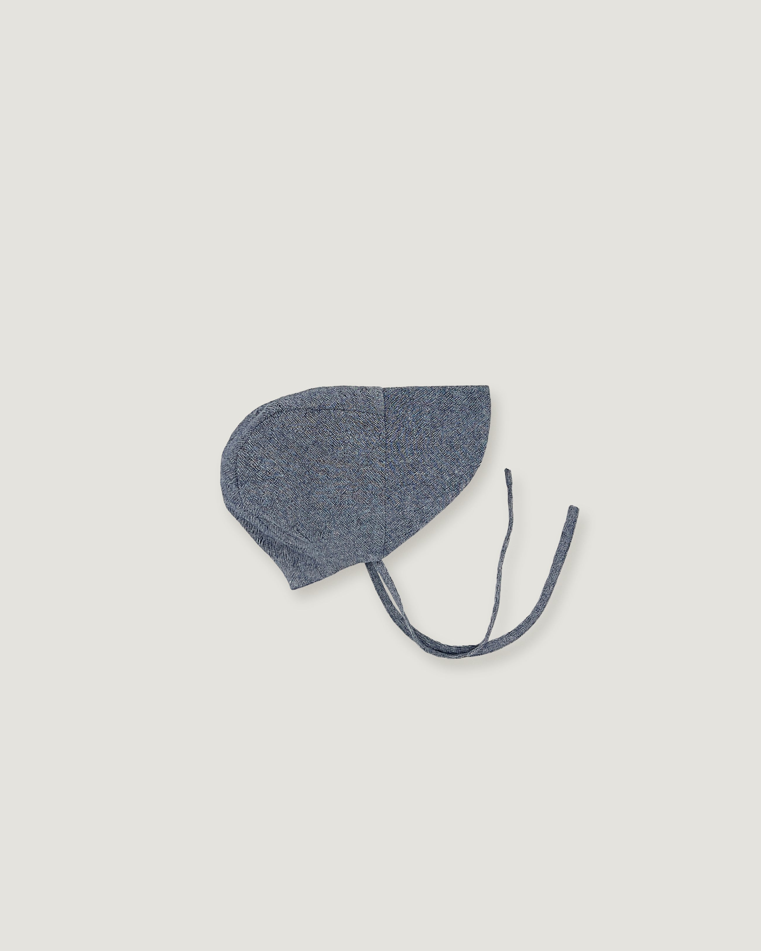 A denim blue linen bonnet with a long visor on a white background