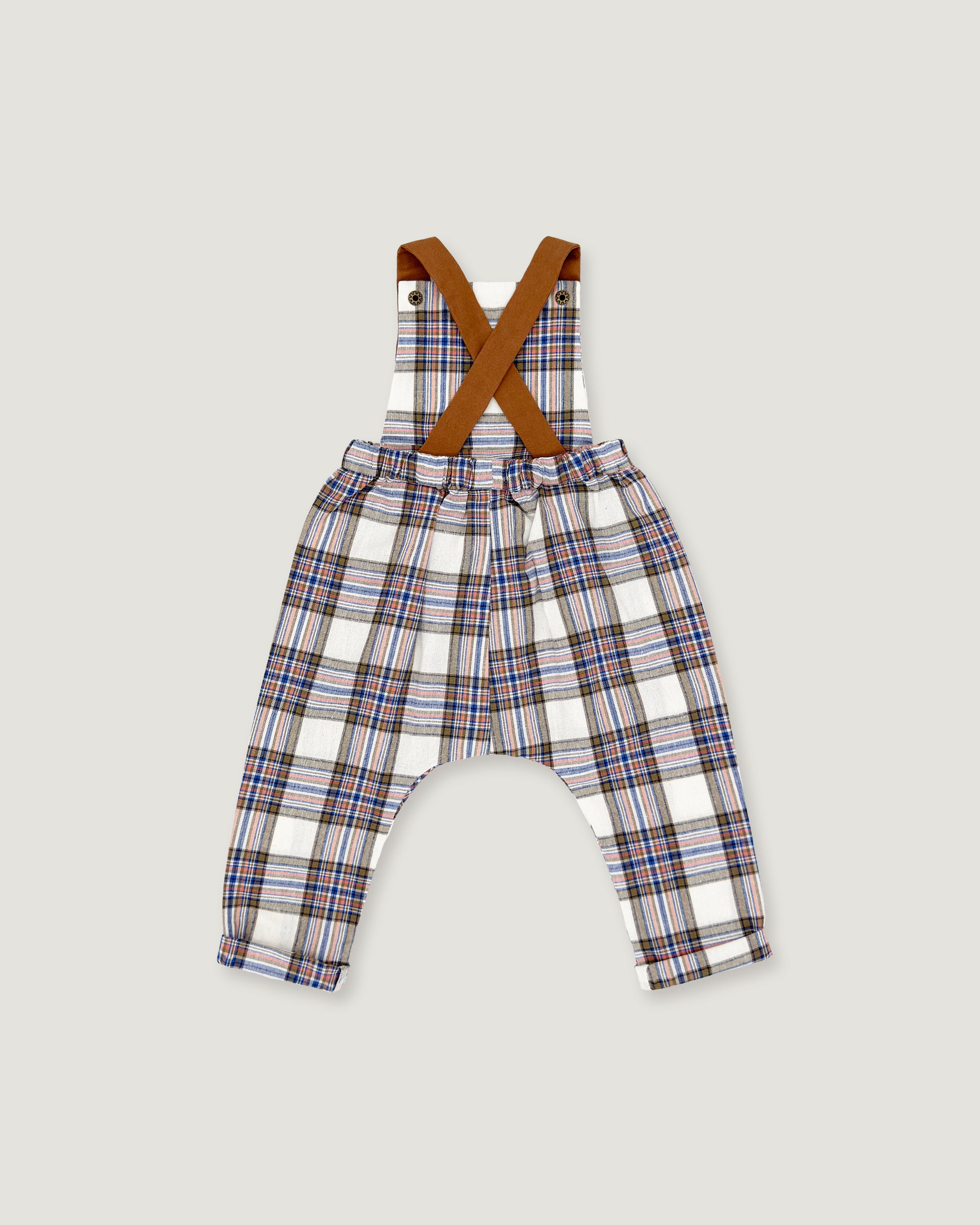 Toddler boy's plaid suspenders with brown crossed shoulder straps, featuring a white base with blue, red, and brown plaid lines, shown flat on a light gray background.