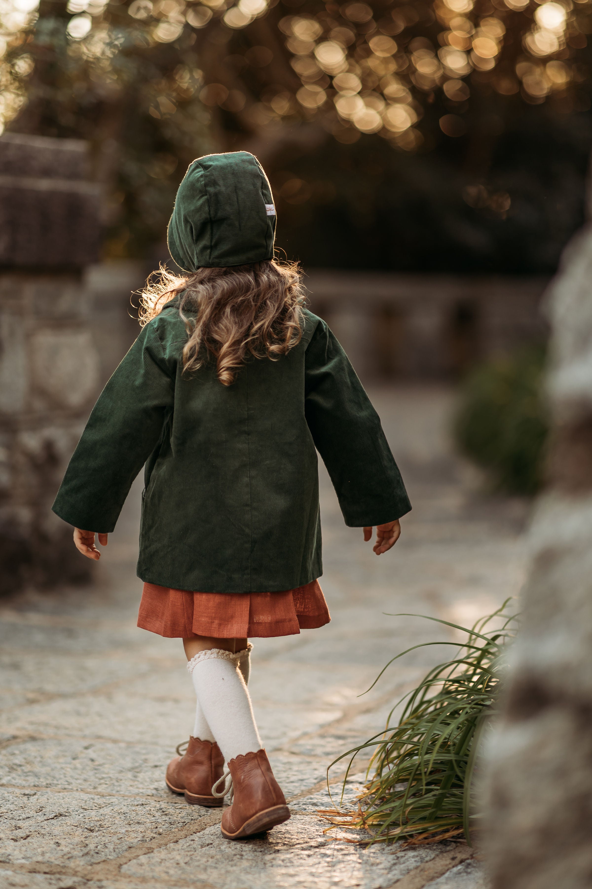 Back view of the girl in the Evergreen bonnet and matching coat, highlighting the quality and durability of sustainable children’s wear for hand-me-downs.