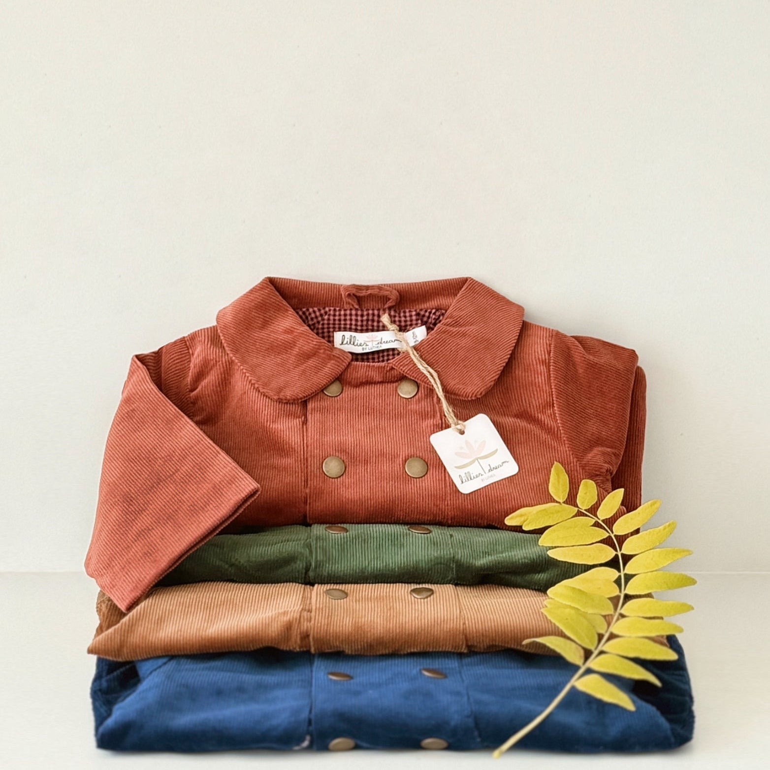 Stack of folded jackets in red, green, brown, and blue with a tag on a white background.