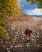 Model girl wearing the Camel Bonnet, in action - Capturing the model engaged in playful activity, this image emphasizes the bonnet’s functionality and stylish appeal as it keeps her warm.