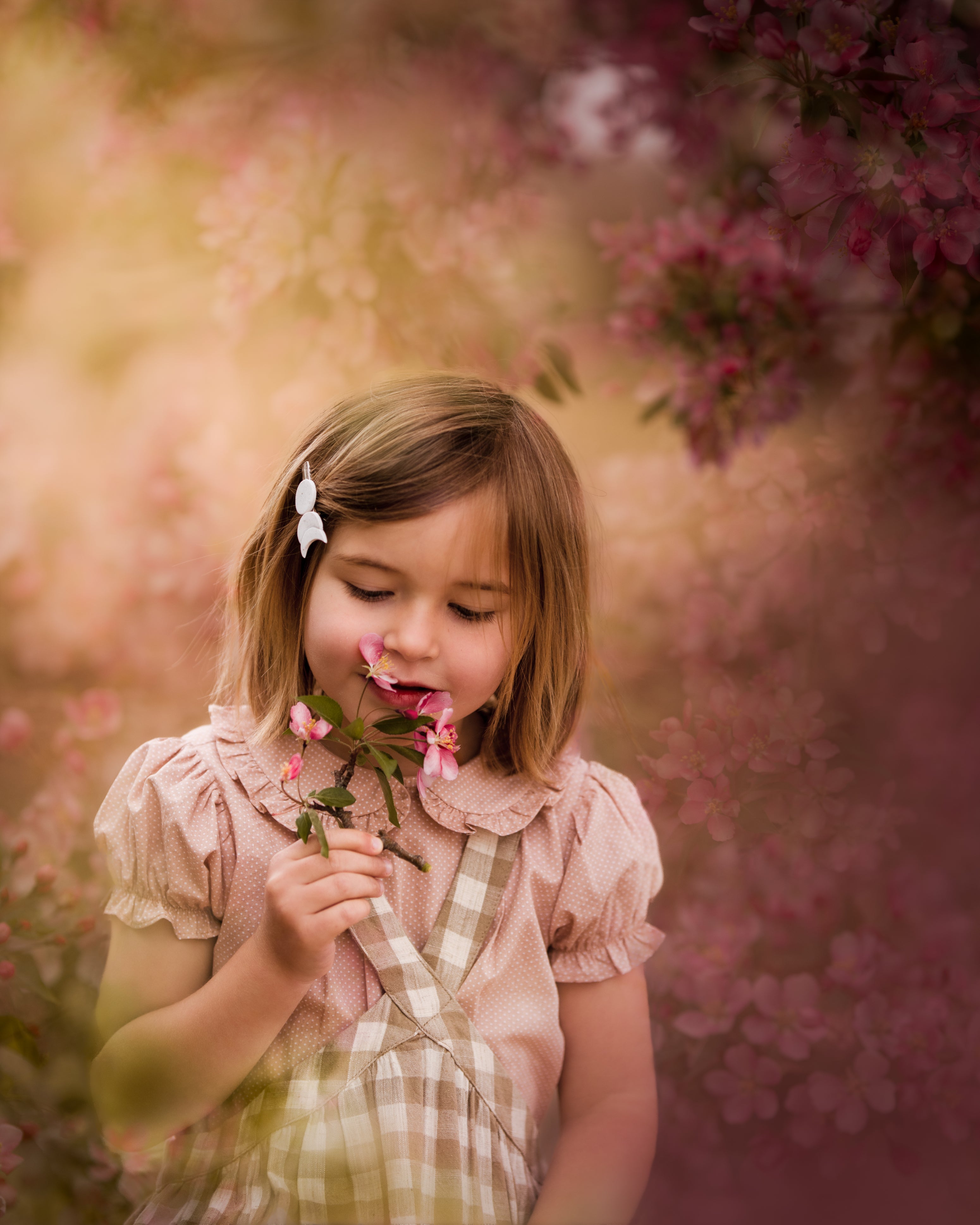 Detail of young girl wearing a beige blouse with white Swiss dots and a matching beige gingham pinafore. The blouse features a Peter Pan collar with ruffles and short puffy sleeves, while the pinafore showcases a classic gingham pattern, perfect for playful outfits.
