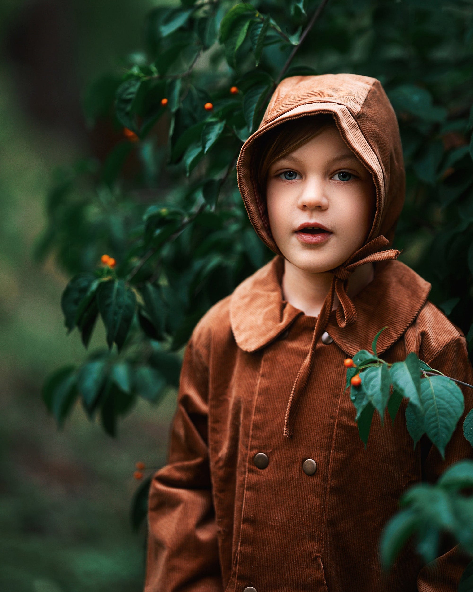 A close-up view of the Camel coat on a boy model. It  reveals the snap closures and Peter Pan collar, ensuring comfort for kids while promoting eco-friendly fashion.