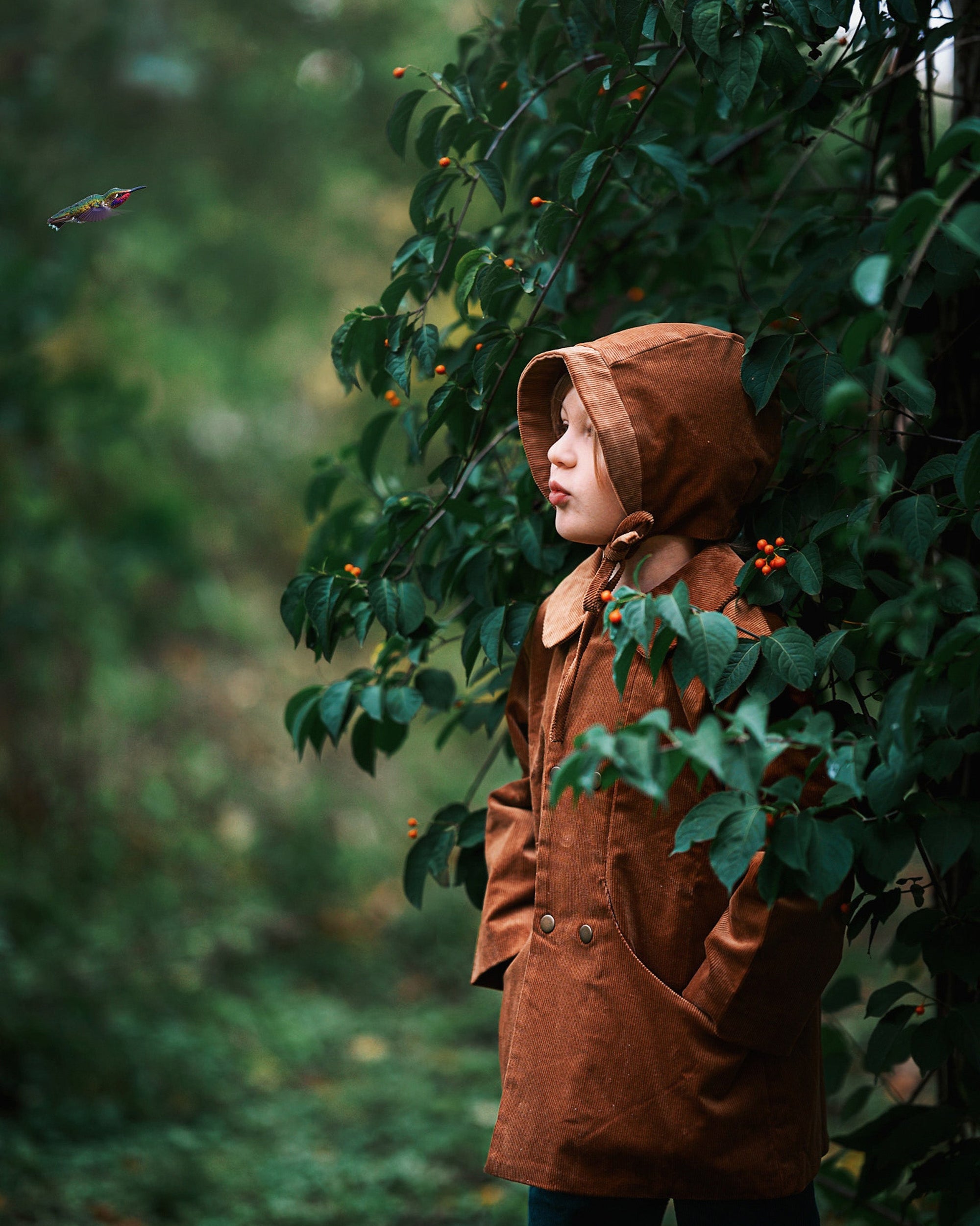 A detailed side view showcases Ezra wearing both the Camel coat and matching bonnet, highlighting the sustainable design that kids will love.