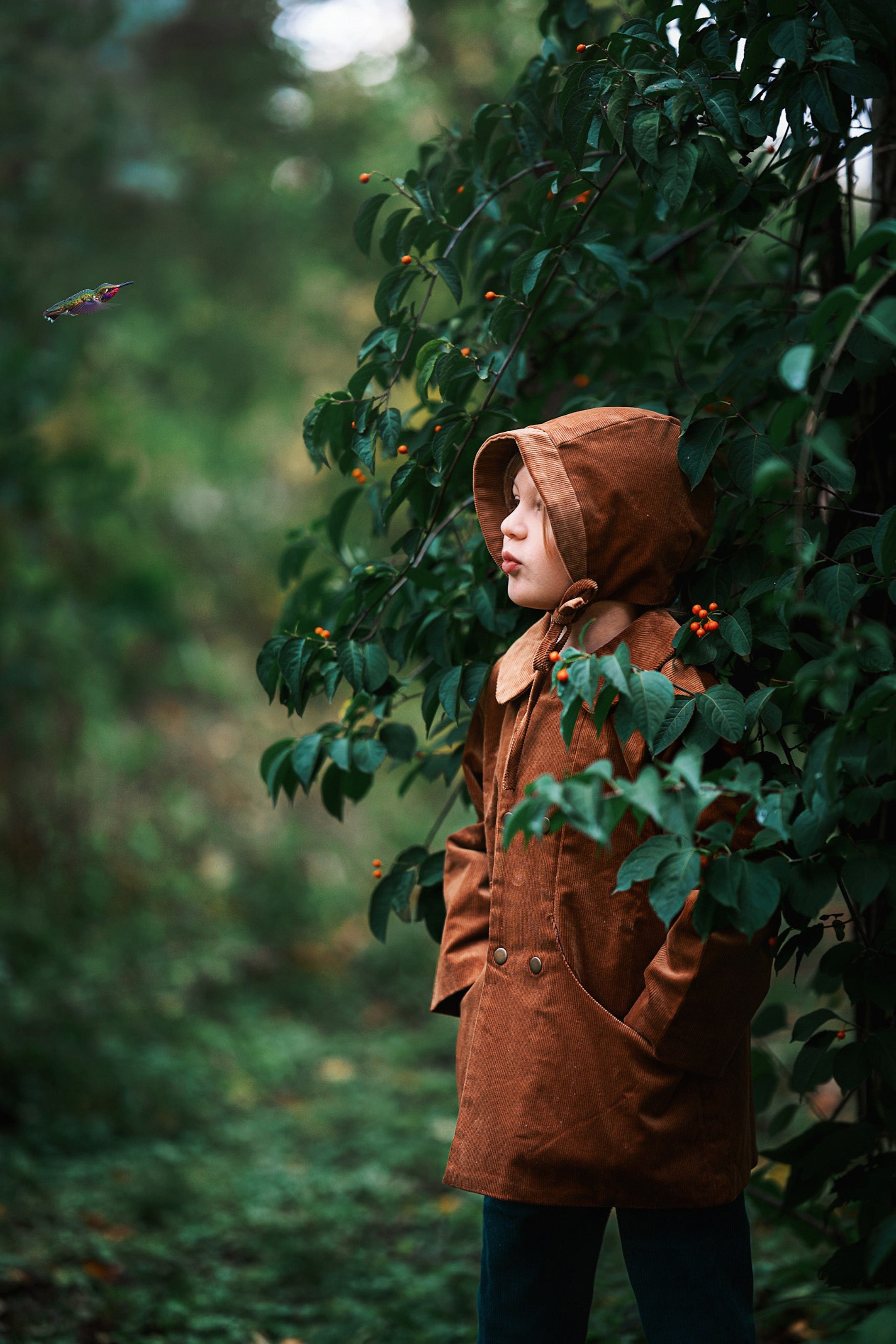 A detailed side view showcases Ezra wearing both the Camel coat and matching bonnet, highlighting the sustainable design that kids will love.