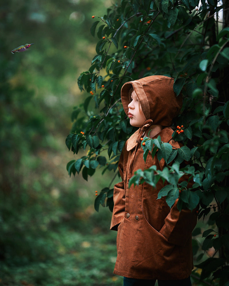 A detailed side view showcases Ezra wearing both the Camel coat and matching bonnet, highlighting the sustainable design that kids will love.