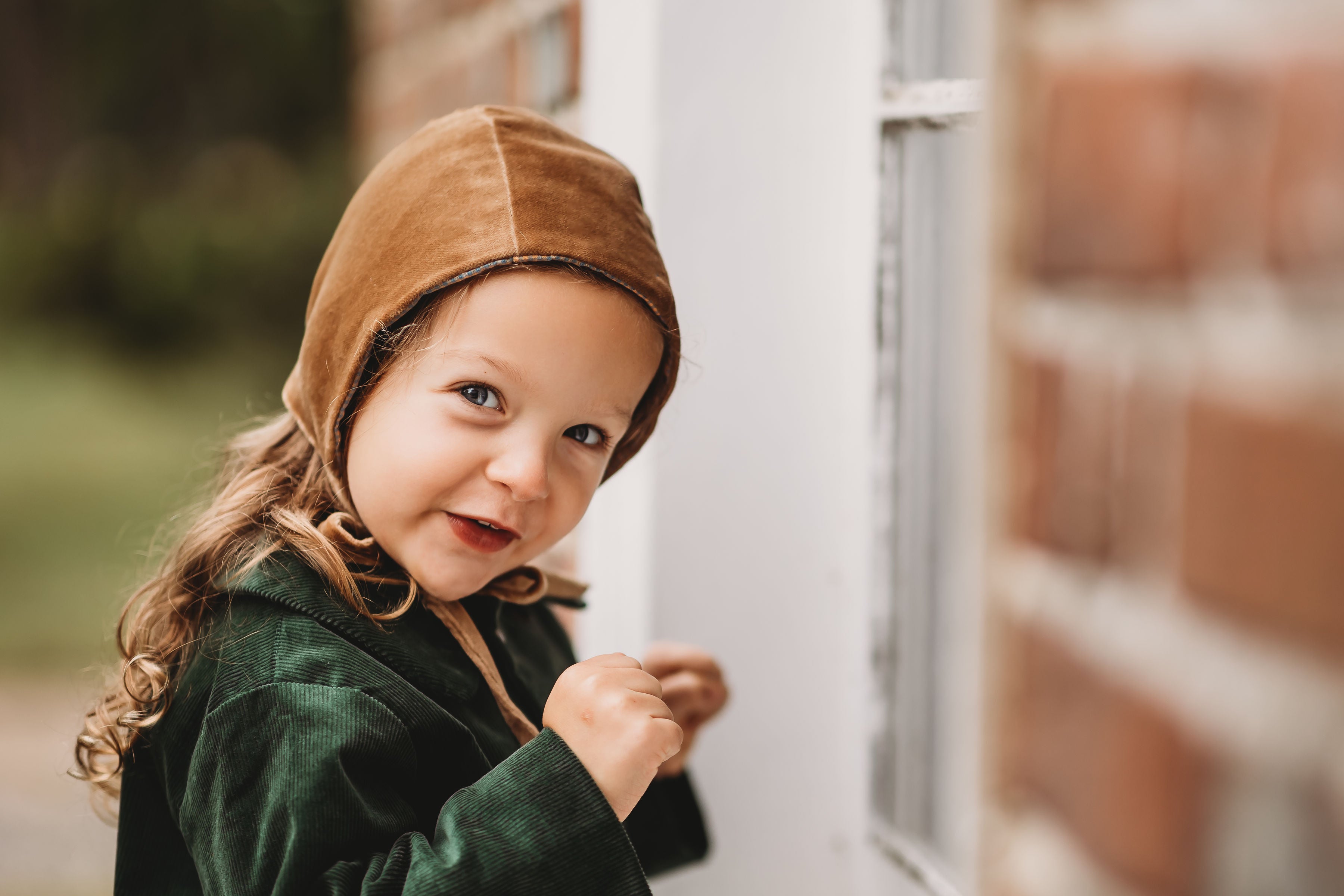 Adorable 3-year-old girl wearing the Gold Velvet Bonnet, capturing the essence of childhood joy and the elegant design of this luxurious accessory.