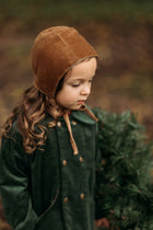 Side view of the Gold Velvet Bonnet on a model, emphasizing the soft brushed gingham cotton interior that provides gentle comfort against delicate skin.