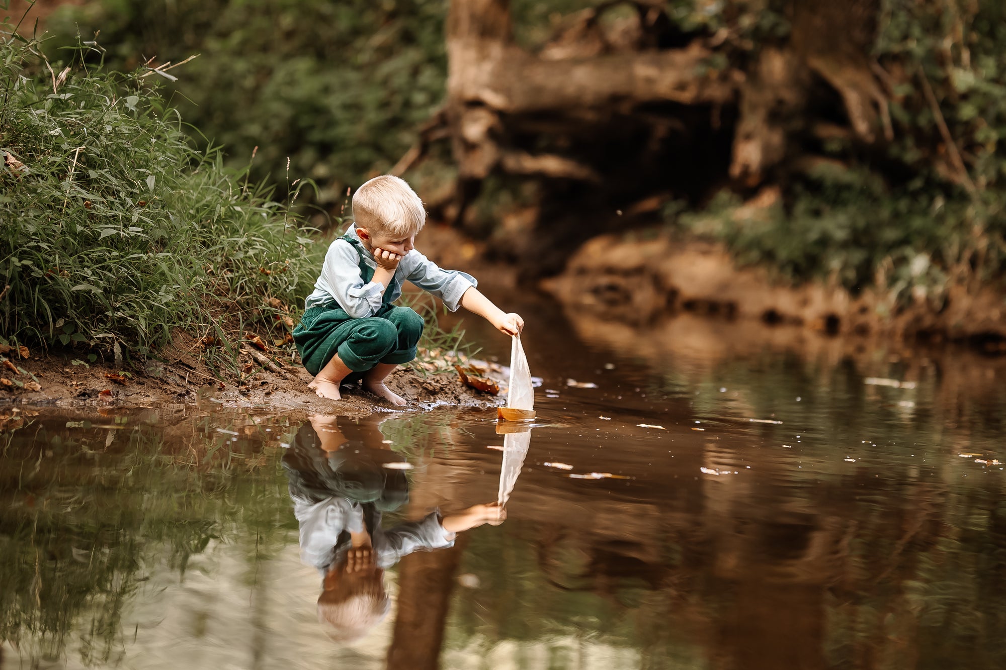 Child playing by a stream with reflection in the water