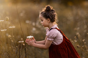 Young girl in a red dress holding flowers in a field