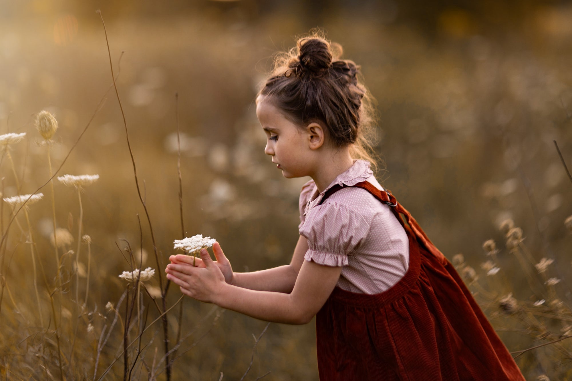 Young girl in a red dress holding flowers in a field