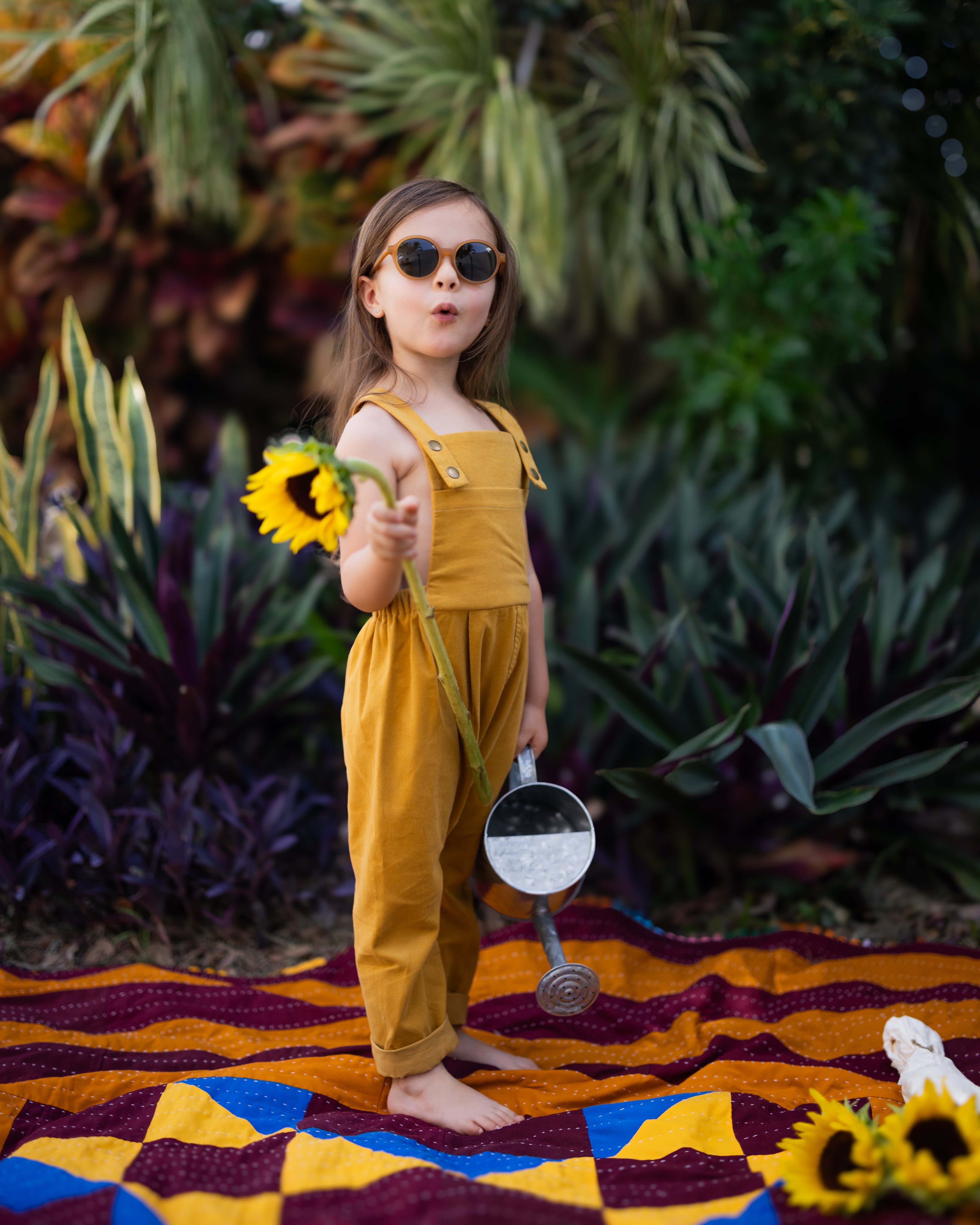 Close-up of the 4-year-old girl in ginger long overalls, displaying the adjustable straps and elegant pleats that add sophistication to the overall look.