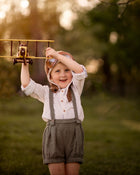 Child holding a toy airplane outdoors with a blurred natural background