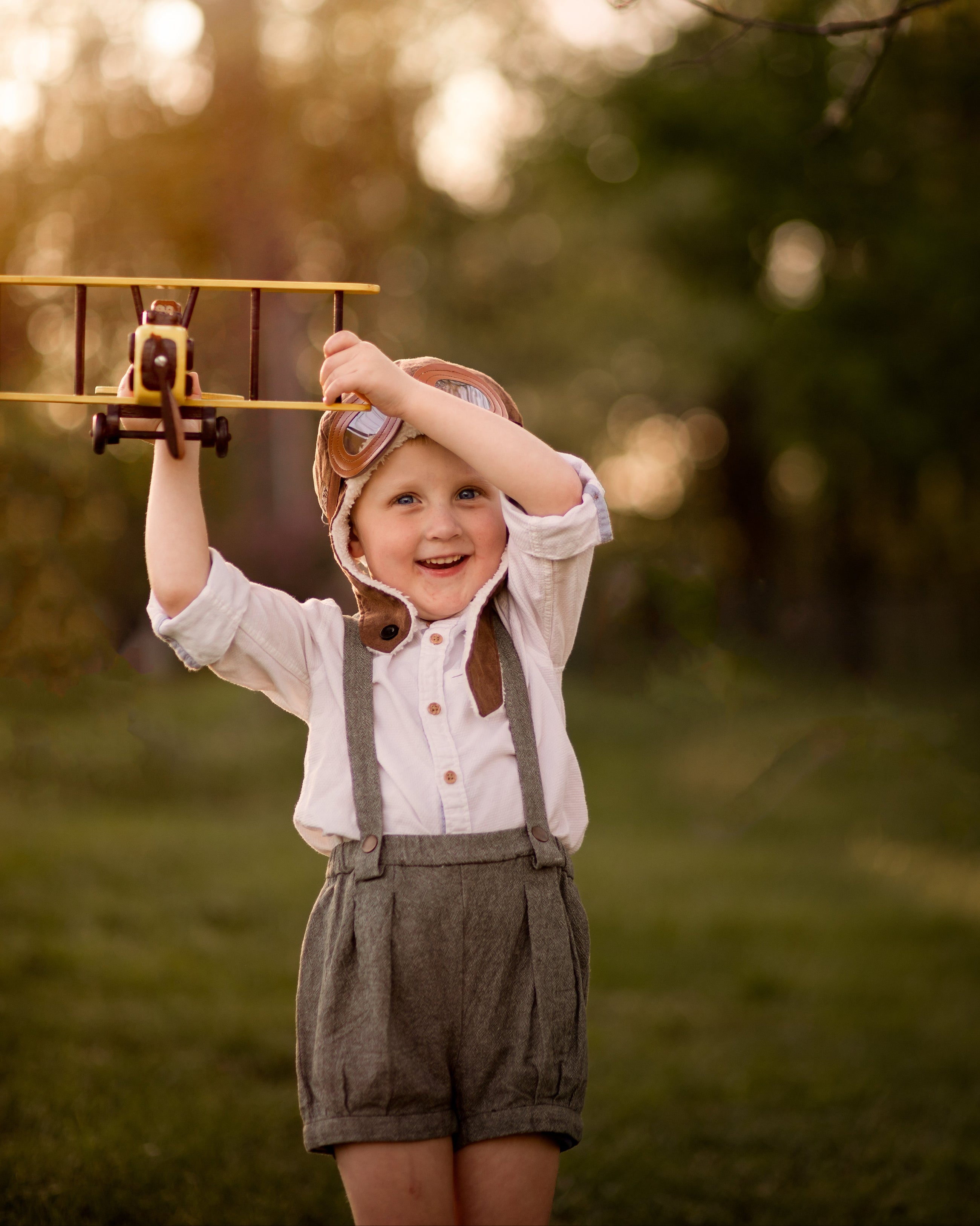 Child holding a toy airplane outdoors with a blurred natural background